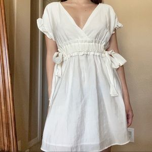 White mini dress, ruched waistline and sleeves, plunging neckline, ties on side